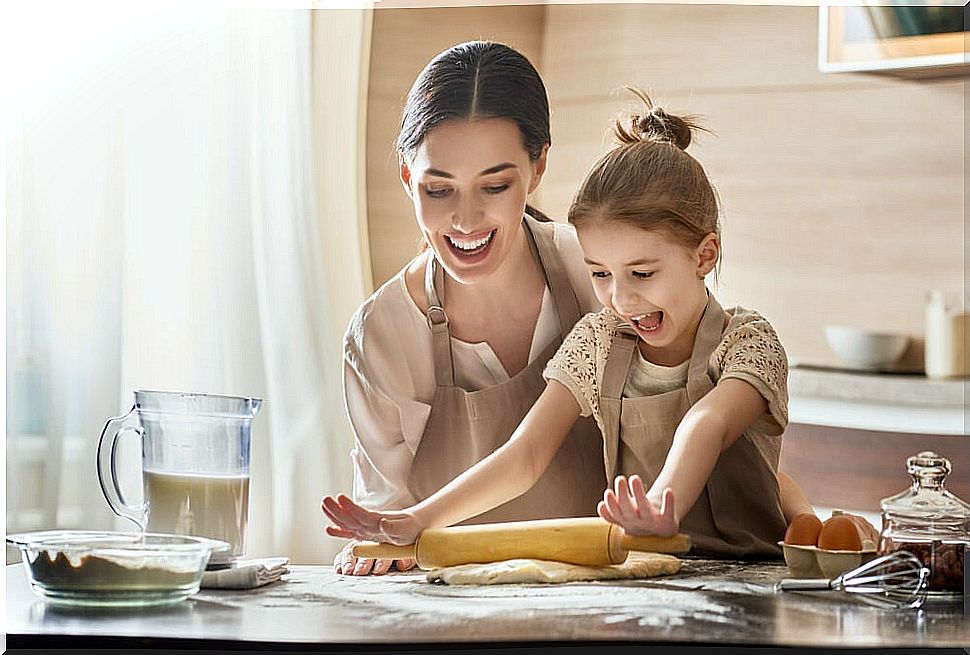 Mother with her little girl helping in the kitchen to be a fun mom.