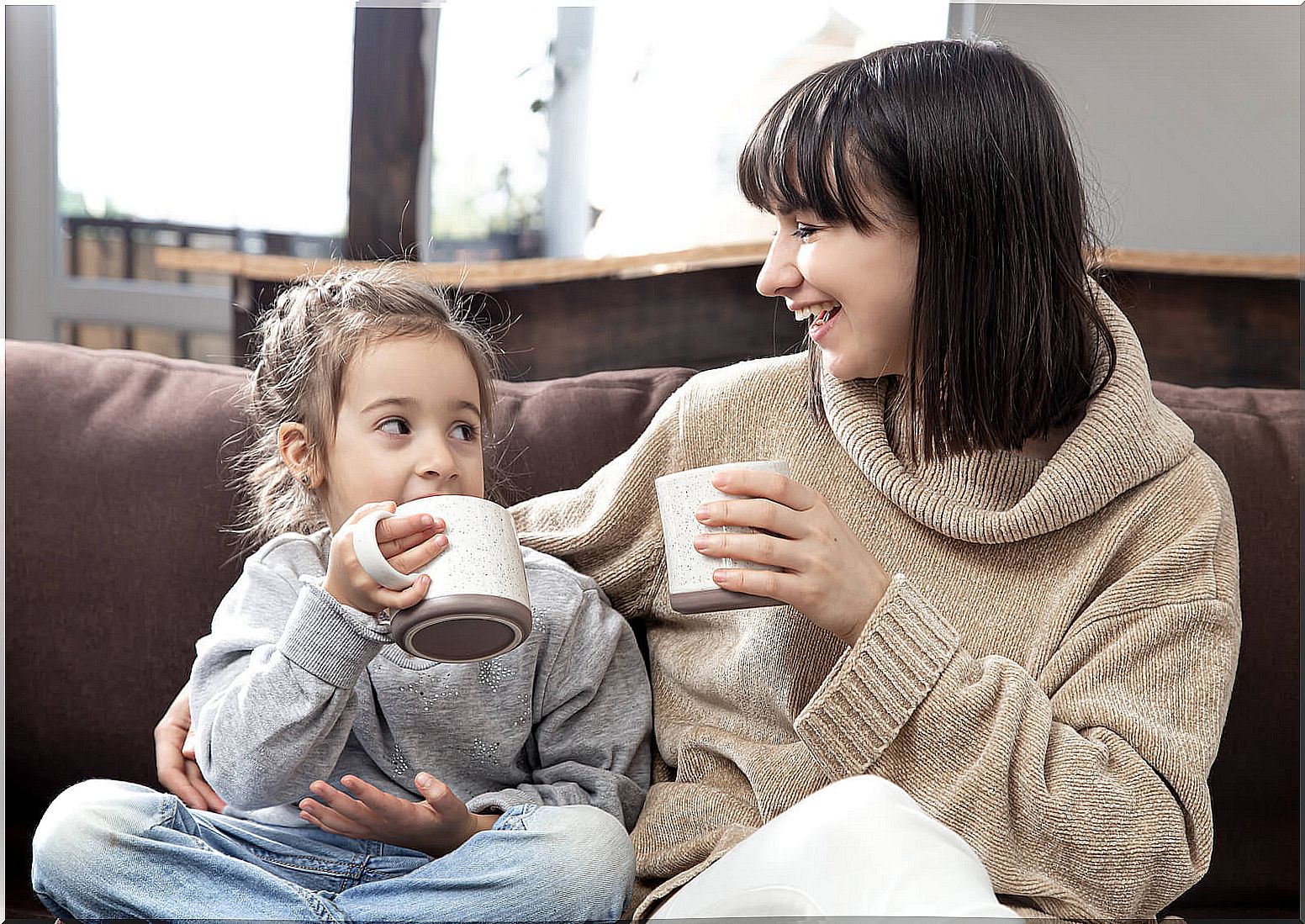 Mother talking with her daughter about how school has gone while they drink chocolate.