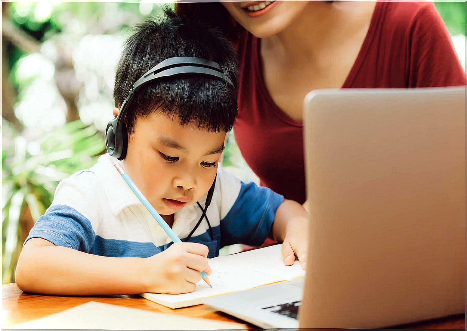 Child with his mother participating in an online creative writing workshop.