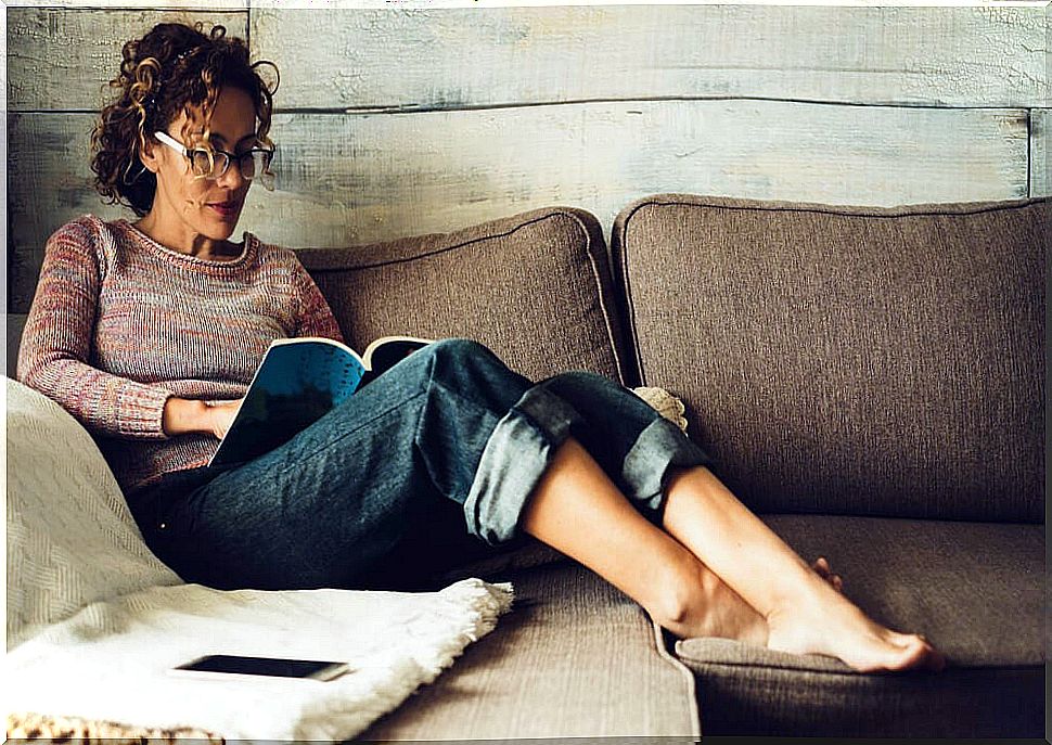 Woman reading one of the new adult books on the couch at home during quarantine.