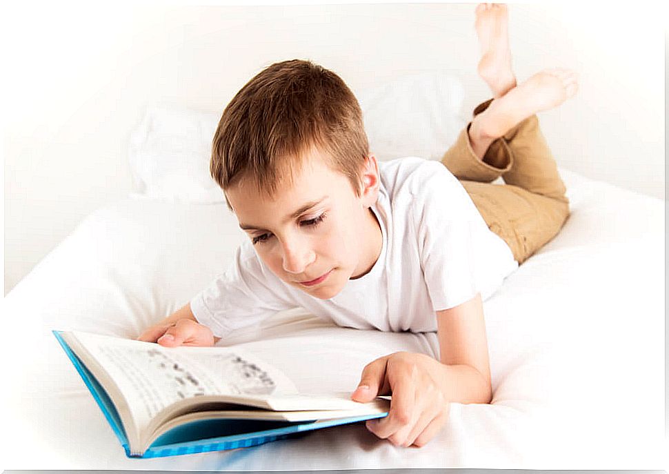 Boy reading one of the books of the Red Series of The Steam Boat in his bed.