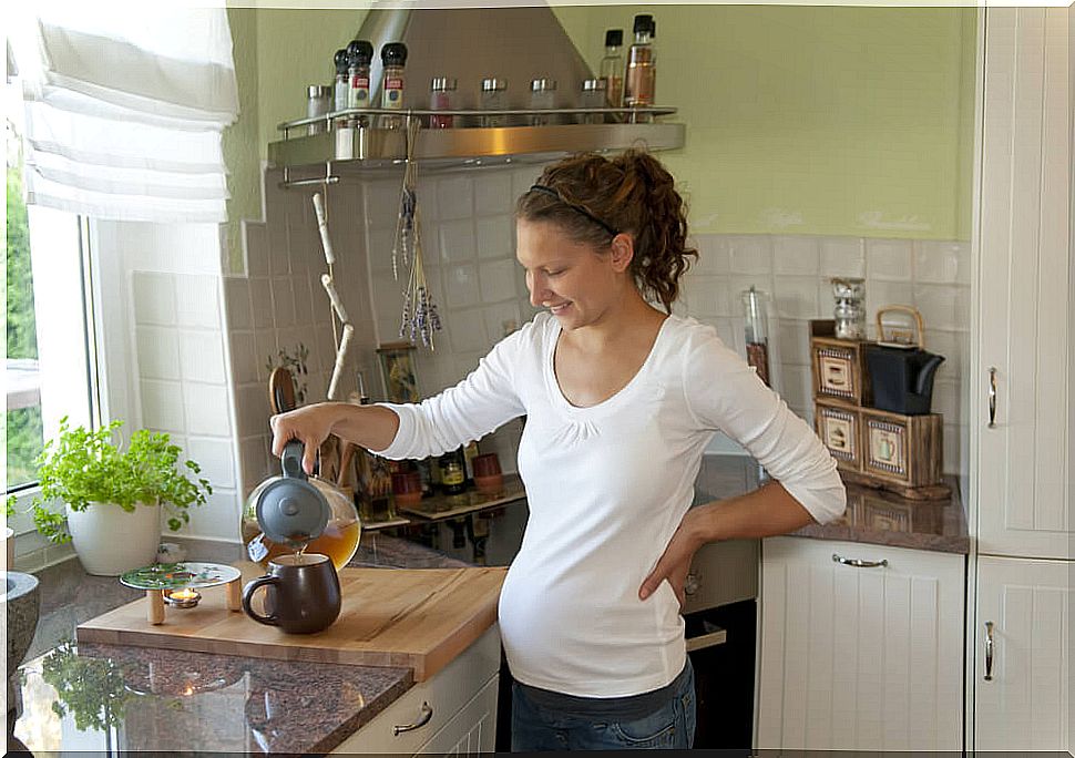 Pregnant woman in her kitchen making an infusion tea.