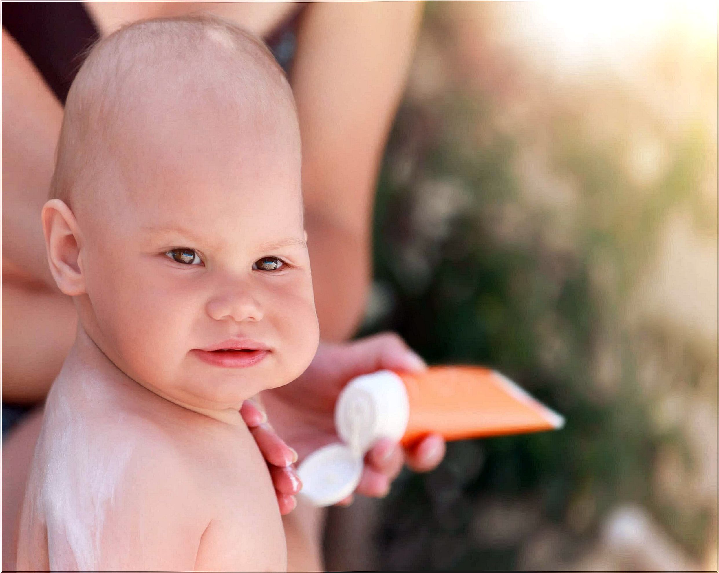 Mother applying sun cream to protect baby's skin.