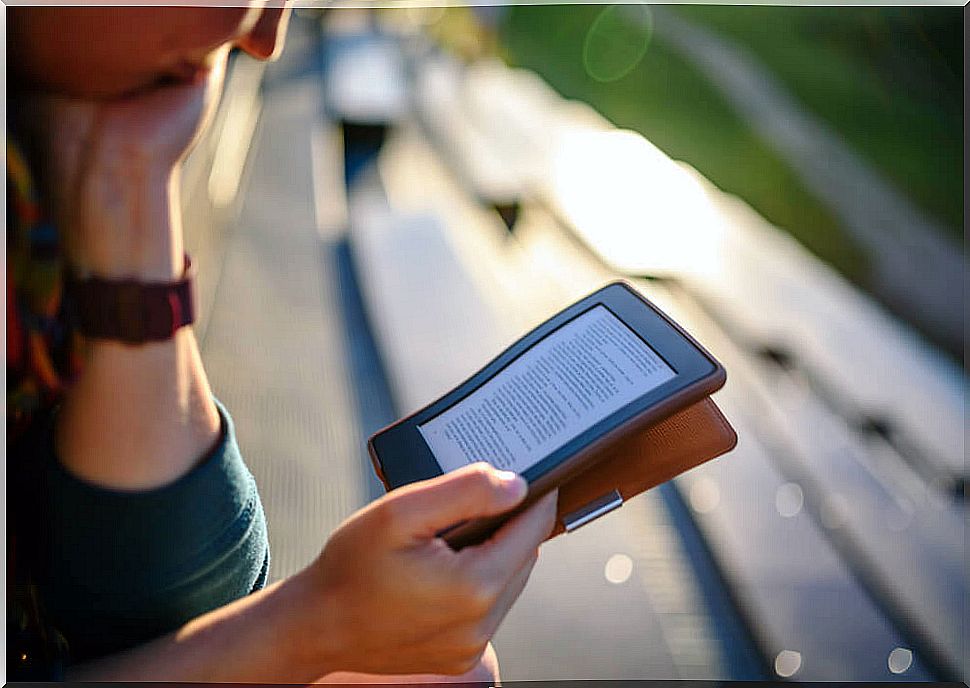 Woman using digital reading platforms on her e-book to read outdoors.