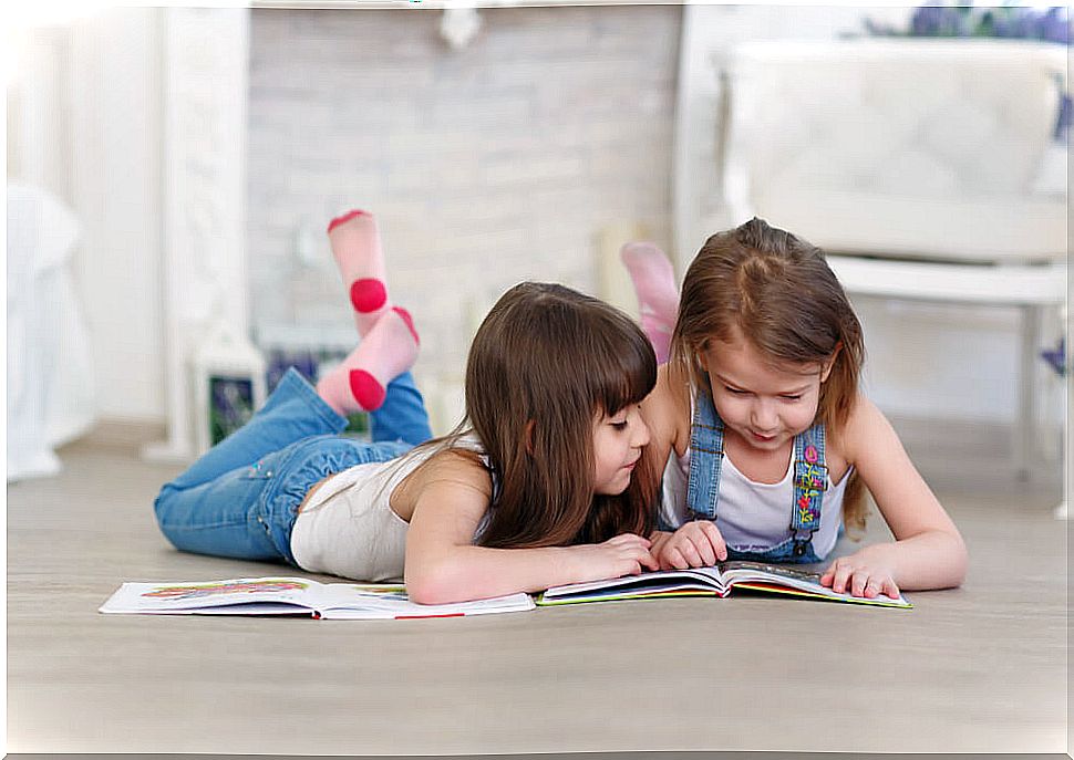 Girls reading children's books lying on the floor to improve attention and concentration.