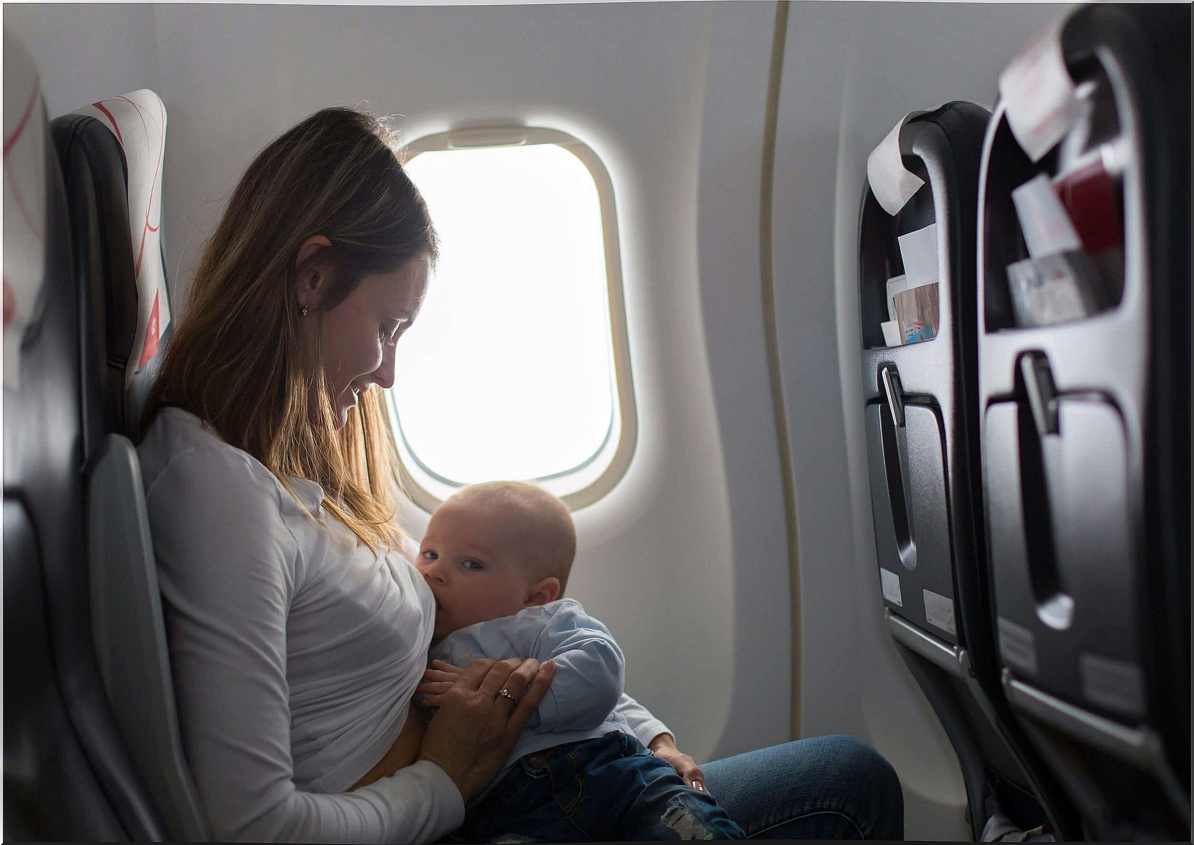 Woman breastfeeds her son on an airplane.