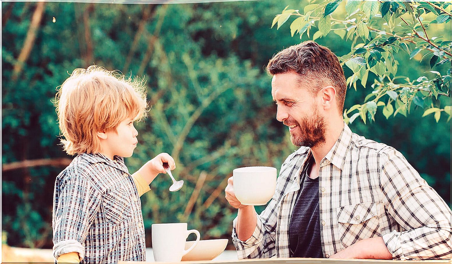 Father to son having a picnic together to teach him good manners.