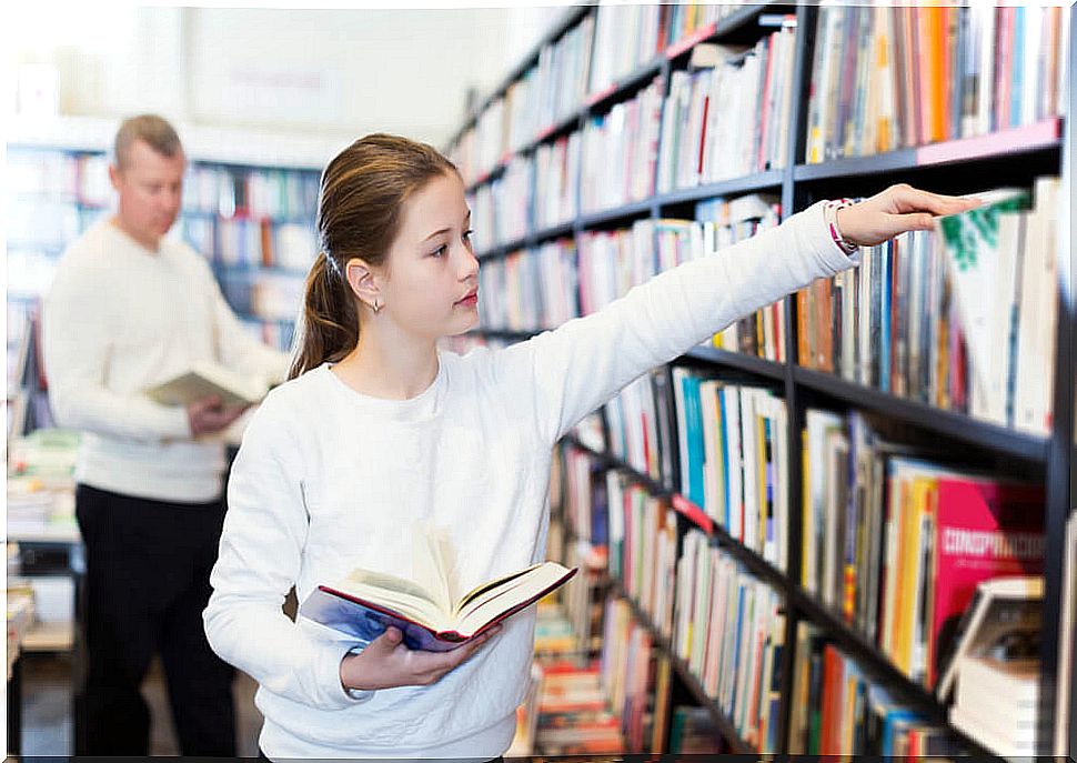 Little girl in the library choosing a new book to read because of her good reading habits.