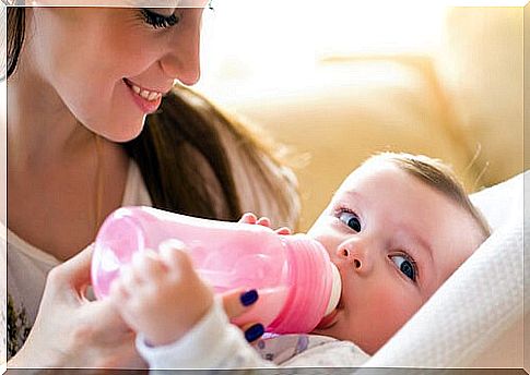 Mother giving sterilized bottle to her baby