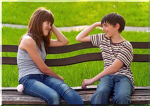 Teenagers in love sitting on a park bench.