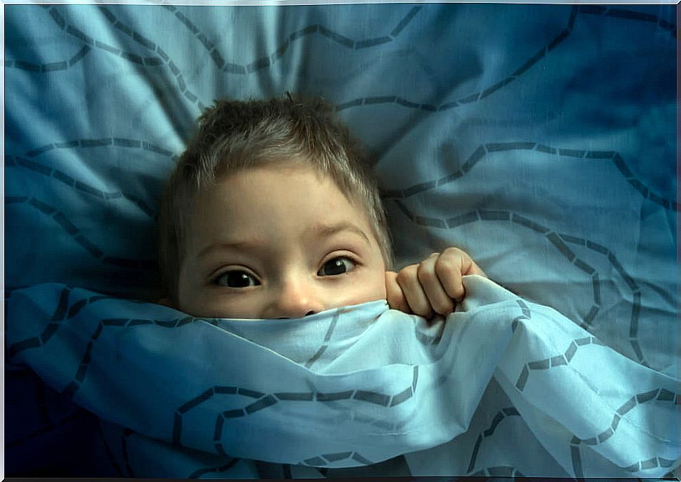 Child lying in bed afraid to go to sleep.