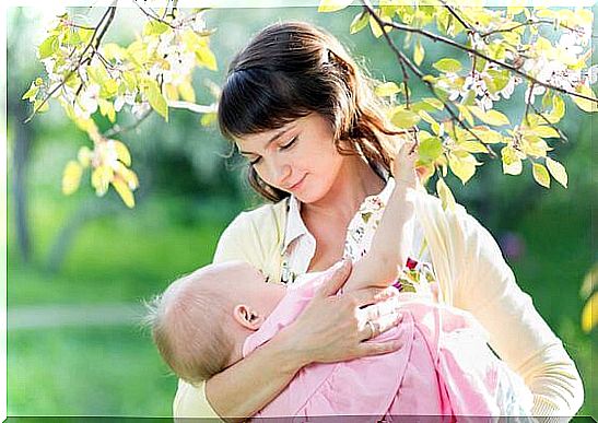 young mother breast feeding her baby girl in garden